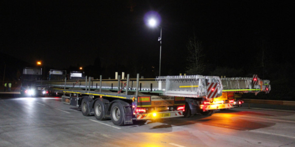 WiB Brückenträger – Stahlträger für moderne Brückenbauprojekte WiB Brückenträger aus Stahl beim Transport und Einbau auf einer Baustelle.